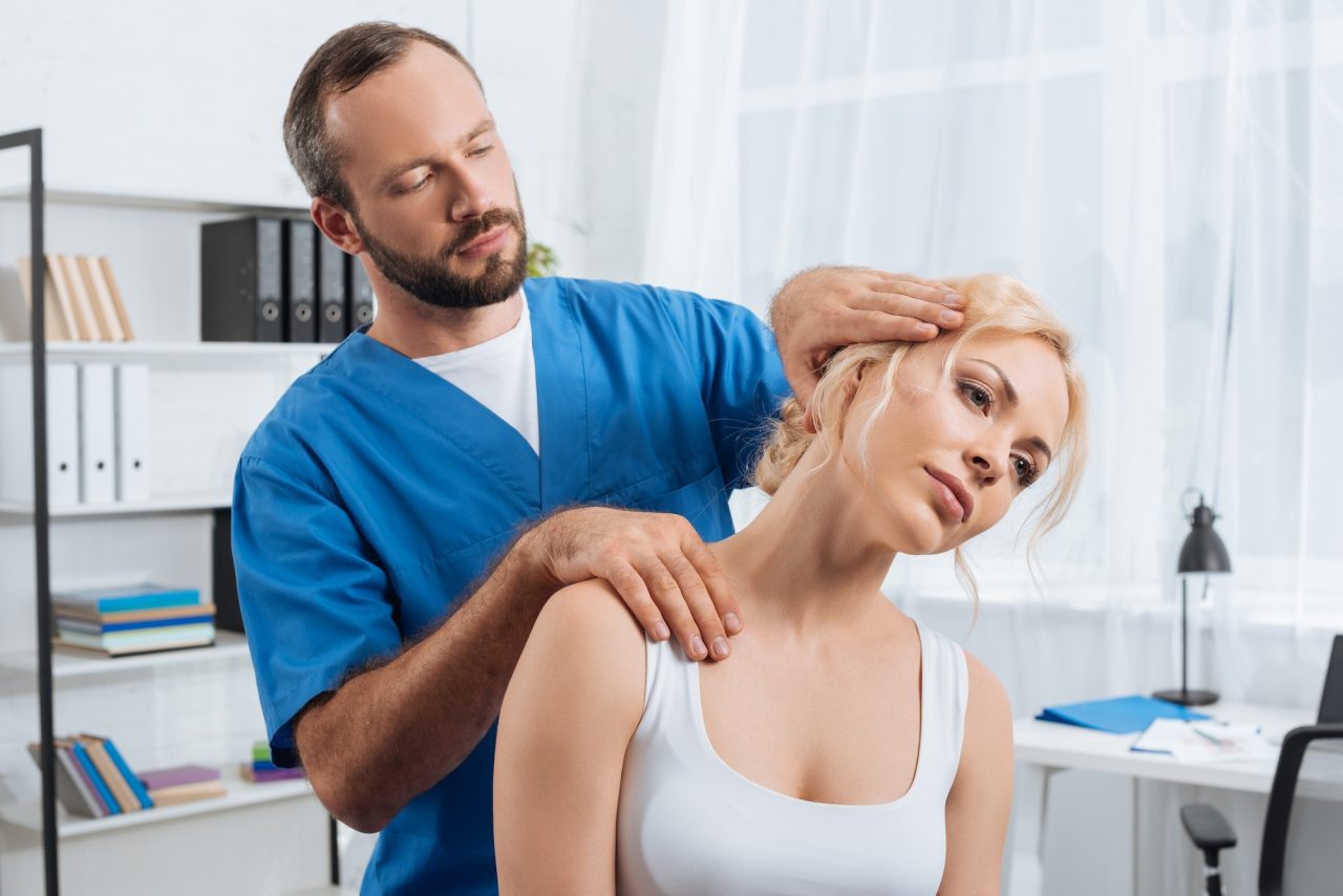 portrait-of-chiropractor-stretching-neck-of-woman-during-appointment-in-hospital.jpg